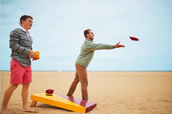 two boys playing cornhole on the beach