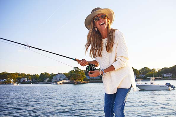 jenny tatelman laughing while holding a fishing rod